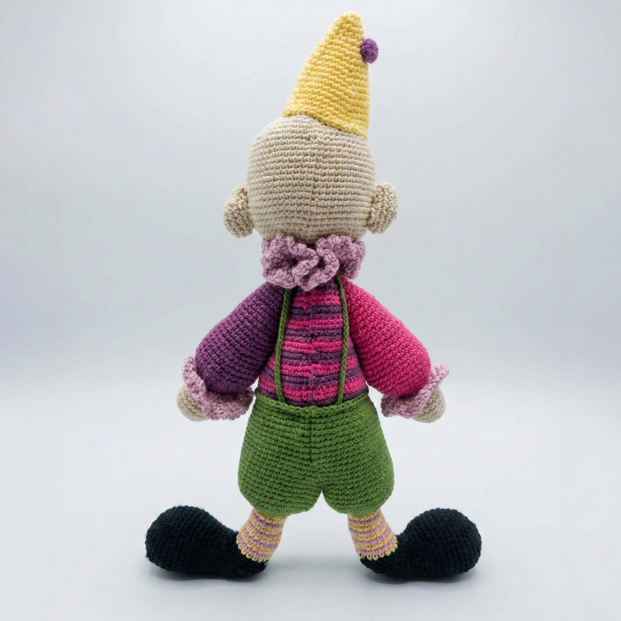 Renkli şapkalı ve kırmızı burunlu el yapımı amigurumi palyaço yan profil görünümü