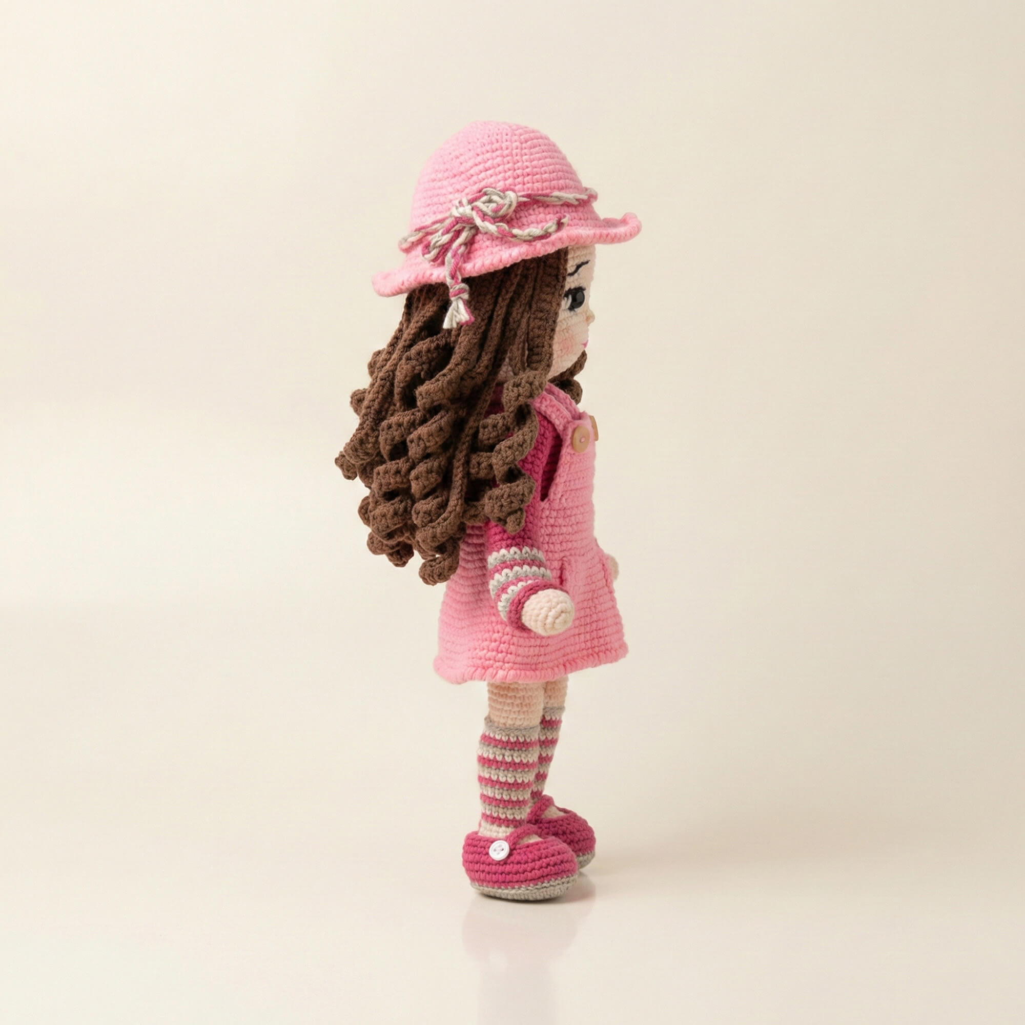 Alize Cotton Gold ip ile örülmüş, hareketli kollara sahip oyuncak bebeğin sağ profilden görünüşü.